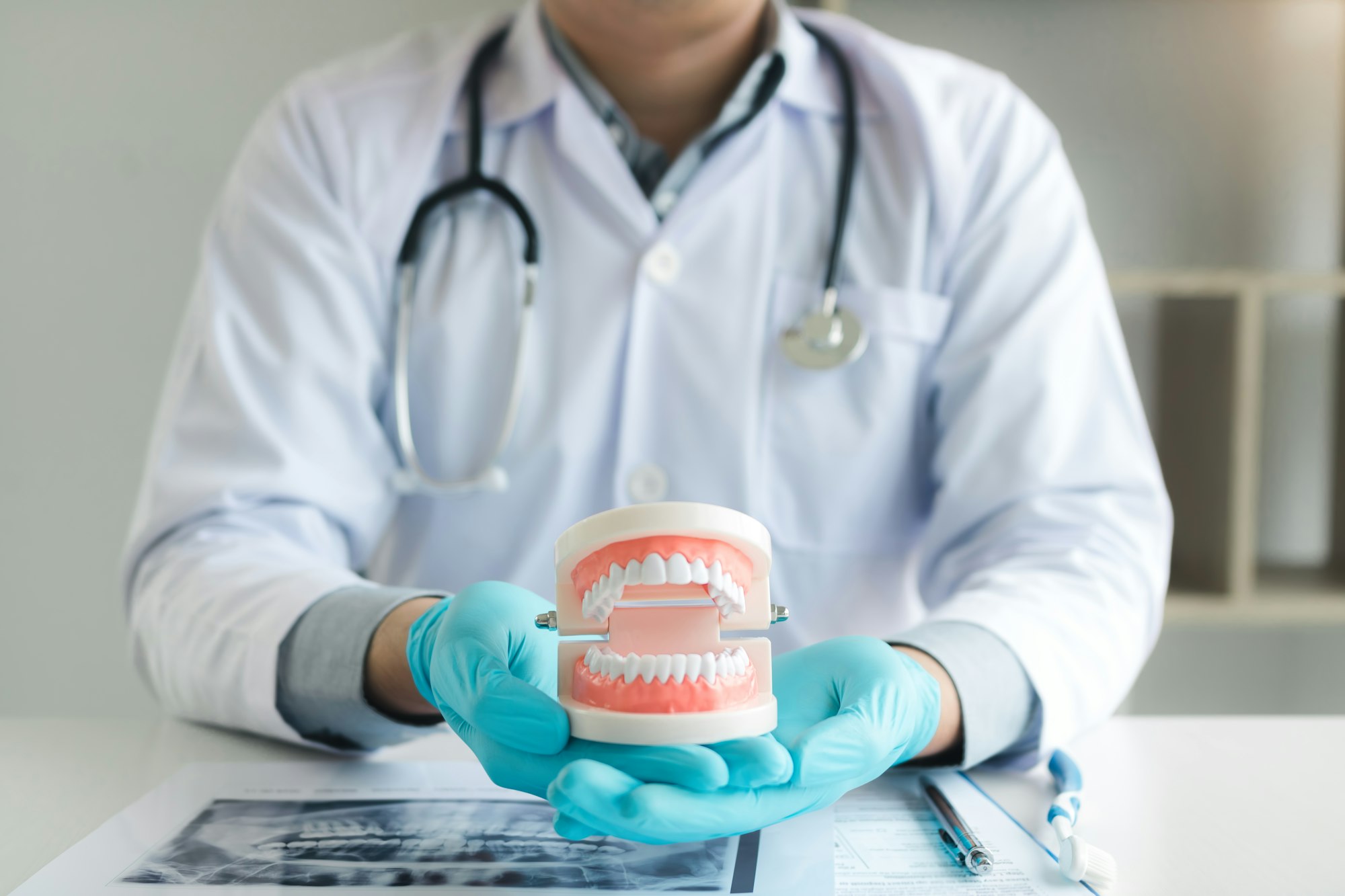 Dentist holding dentures in office room.