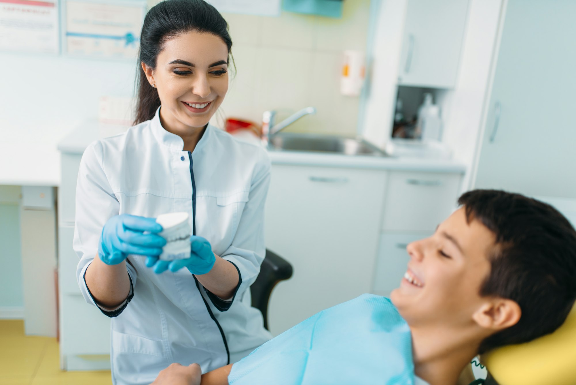 Female dentist shows dentures to little boy