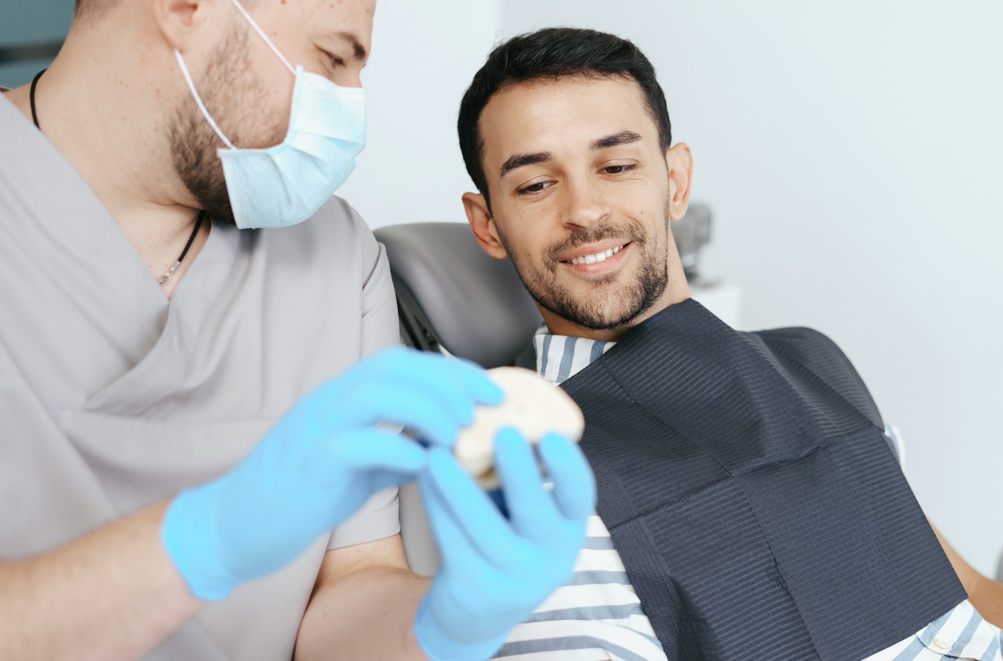 Male dentist showing patient the artificial dentures