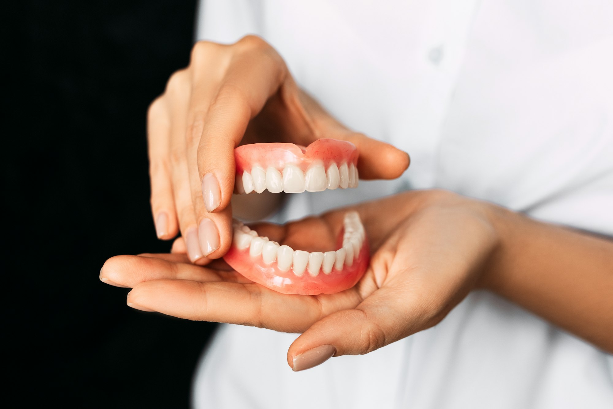 The dentist is holding dentures in his hands. Dental prosthesis in the hands of the doctor close-up