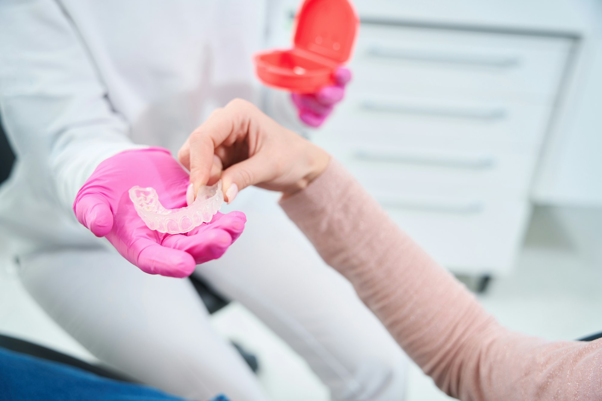 Woman takes a special mouthguard from hands of an orthodontist