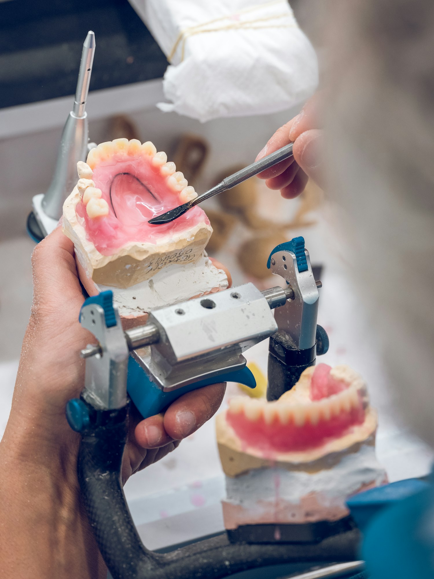 Crop senior dental technician shaping denture with spatula