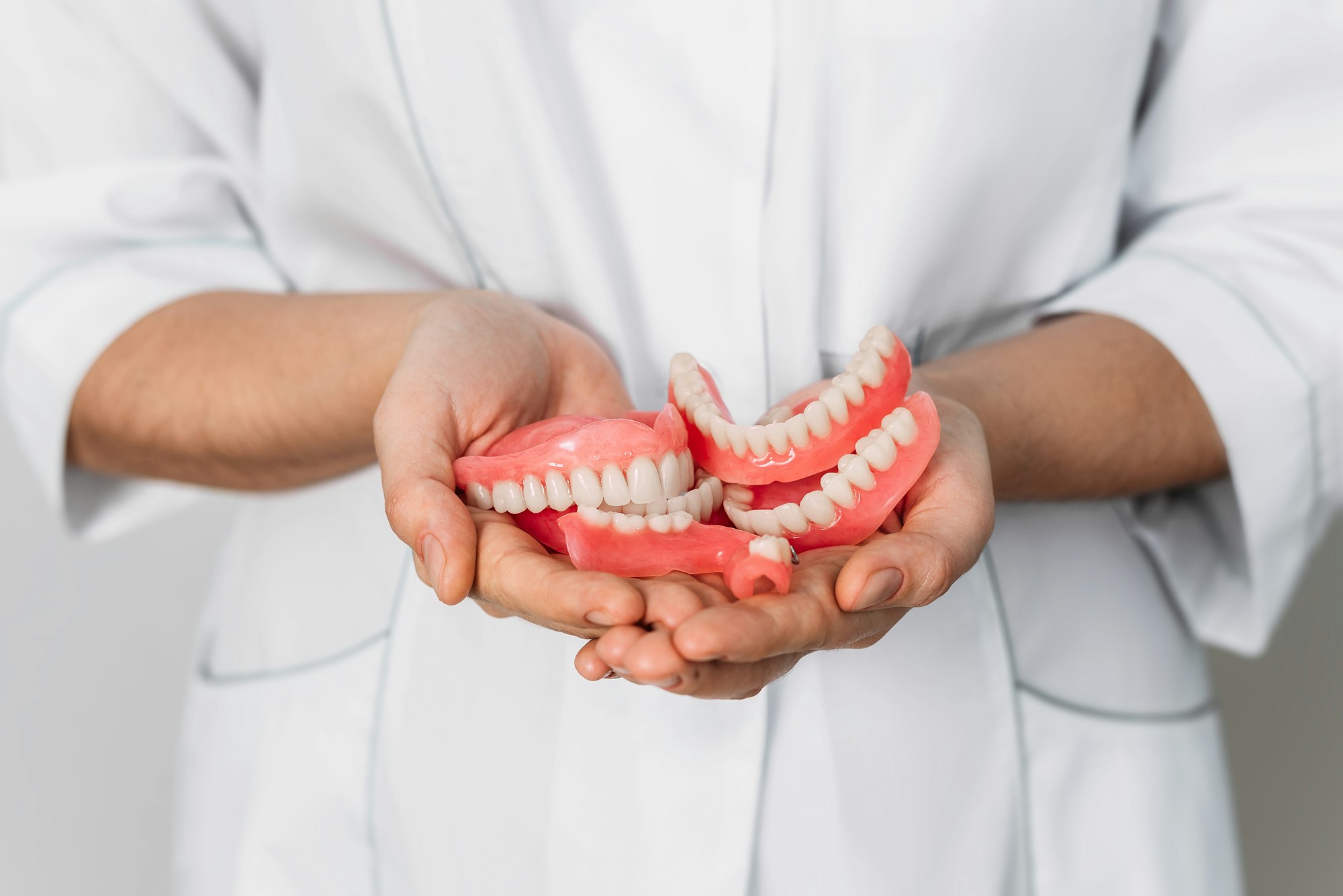 An orthopedic dentist holds dentures in his hands. Dentures in the hands of a doctor