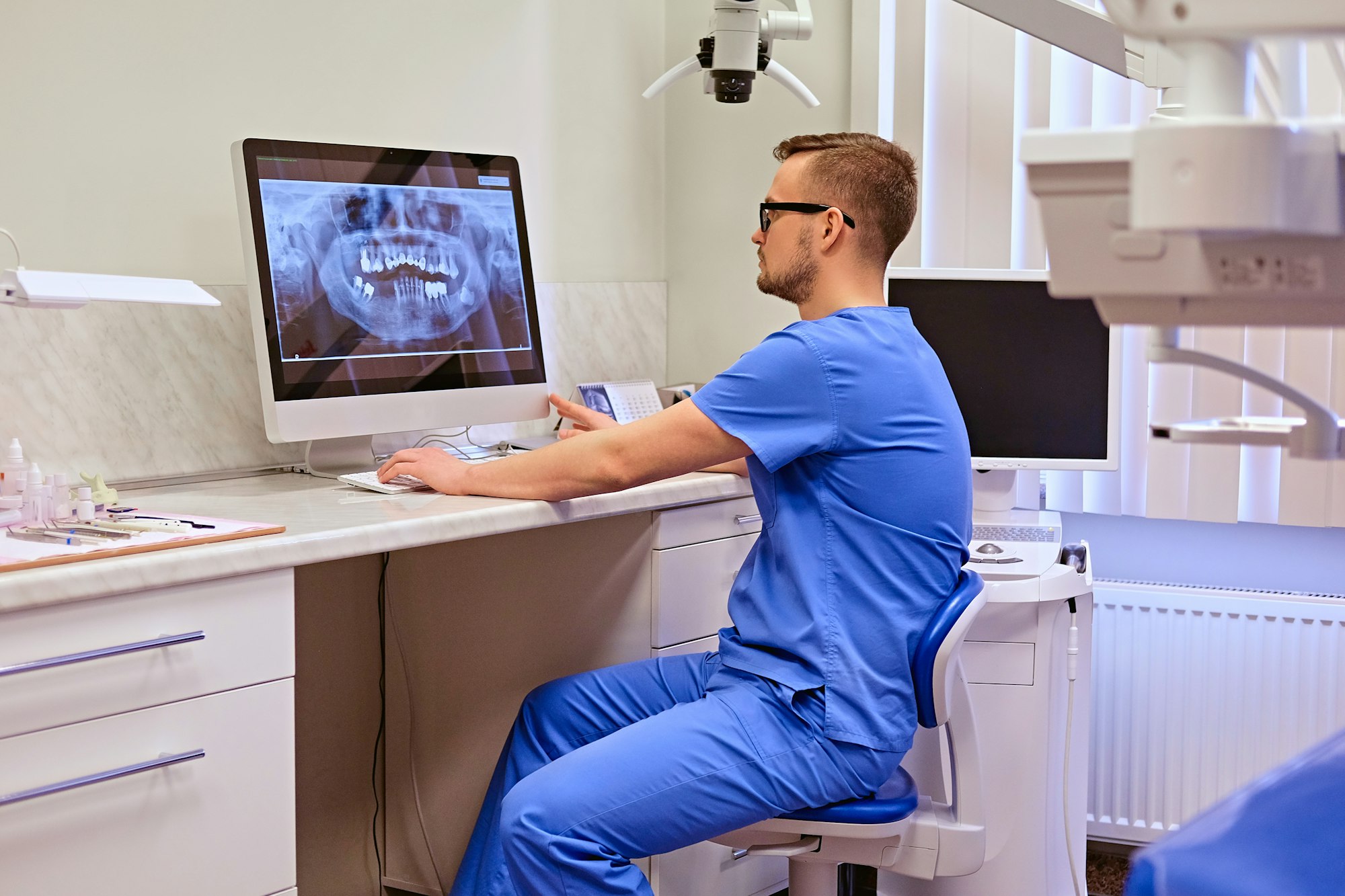 Dentist looking at teeth x-ray on the computer in a dentist office.