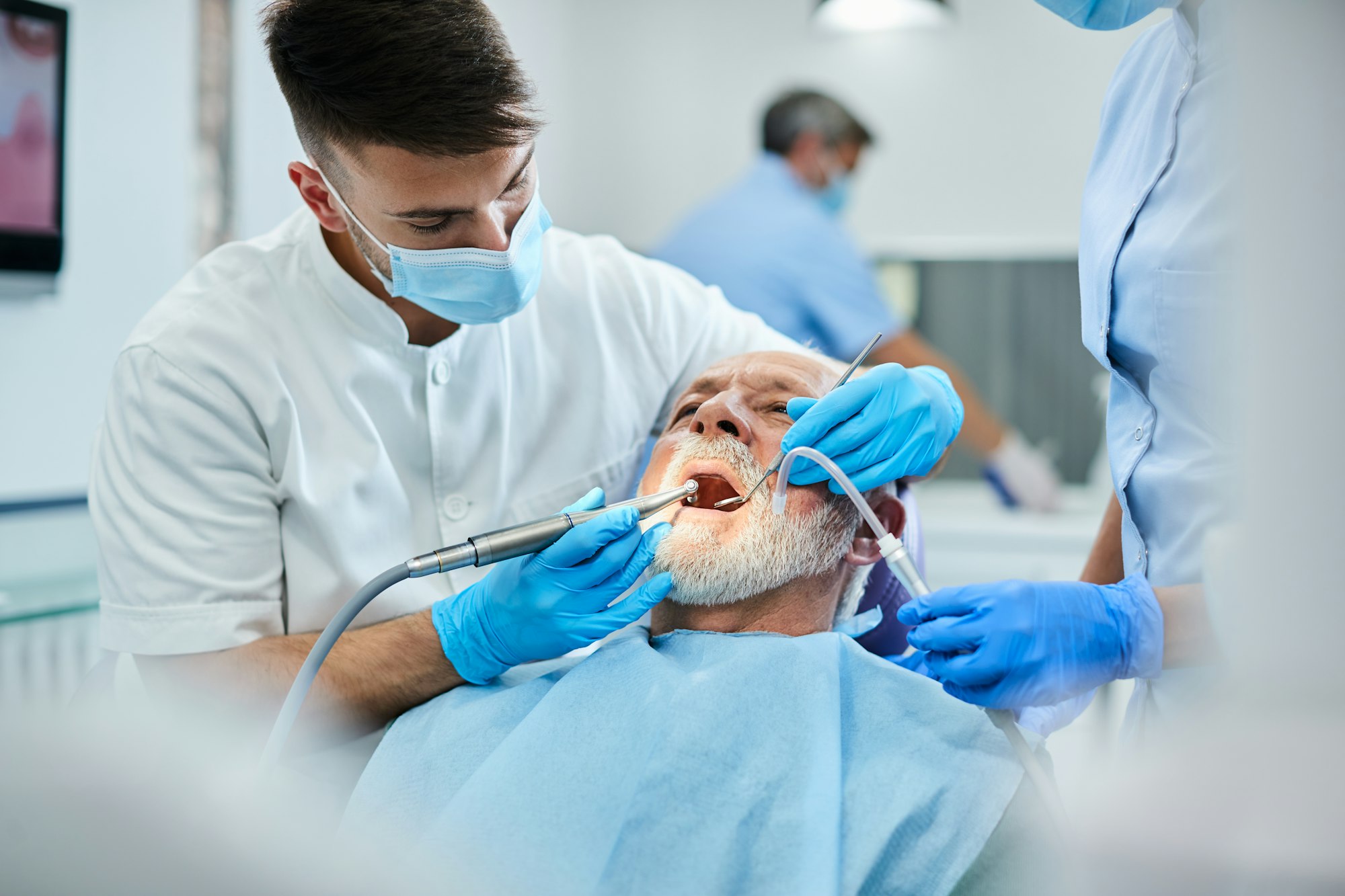 Senior man having teeth polish procedure during appointment with dentist at clinic.