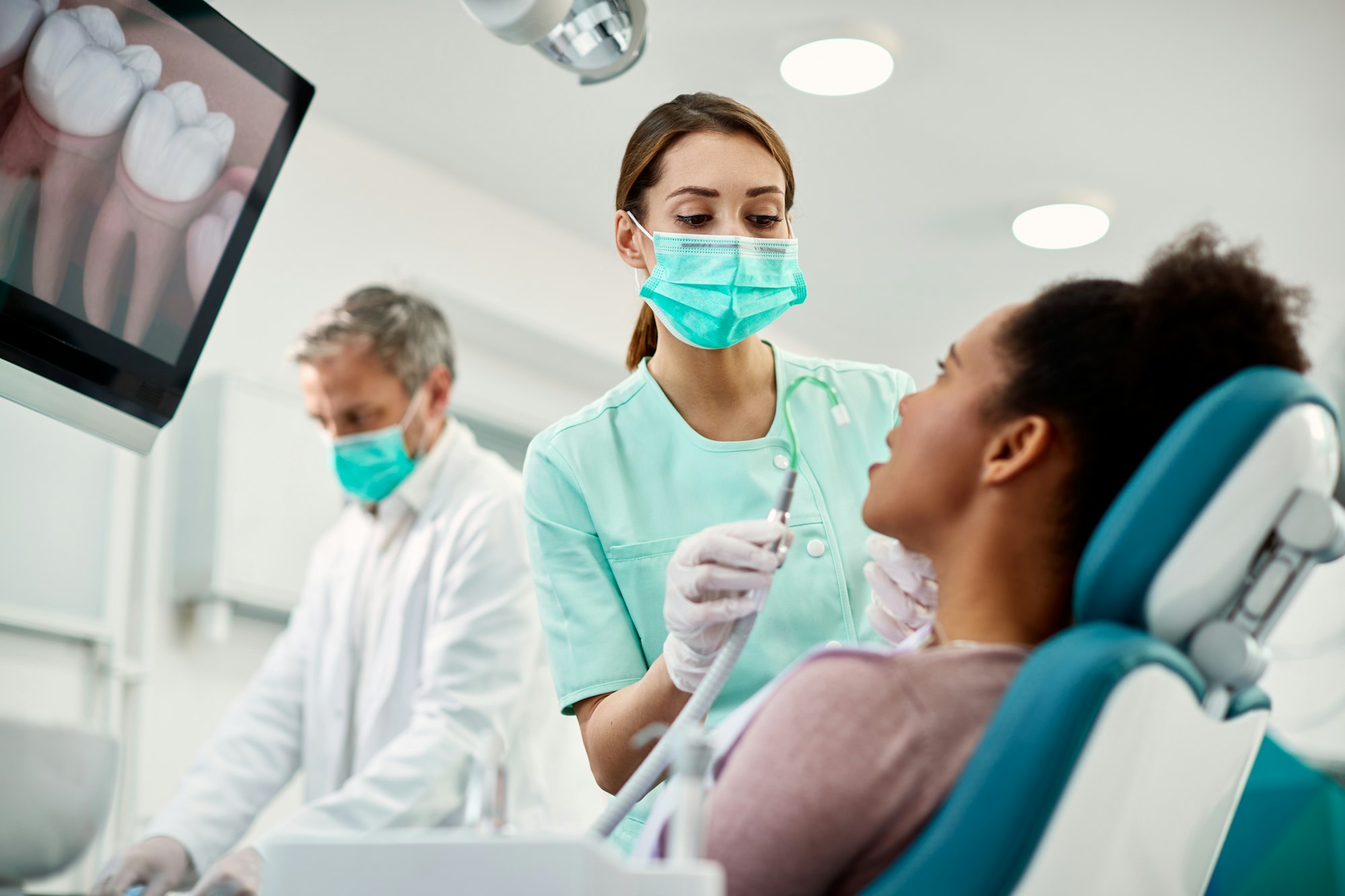 Young nurse preparing patient for dental procedure at dentist's office.