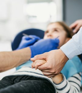 Annual dental check-up of a child with father in dentist surgery