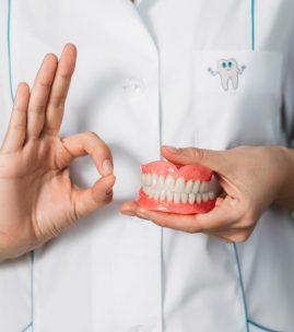 Dental prosthesis in the hands of the doctor close-up. Front view of complete denture