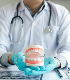 Dentist holding dentures in office room.