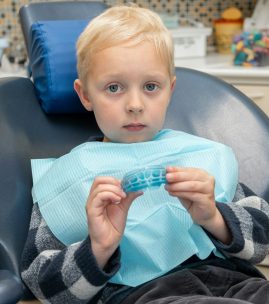 Little boy at dentist's office. Doctor dentist shows Silicone dental mouthguard. Orthodontic trainer