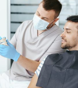 Male dentist showing patient the artificial dentures