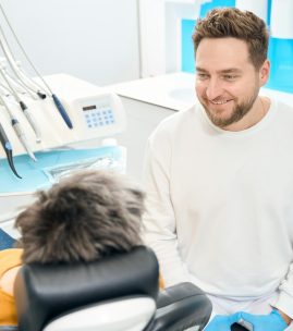 Smiling male dentist undertaking new patient examination